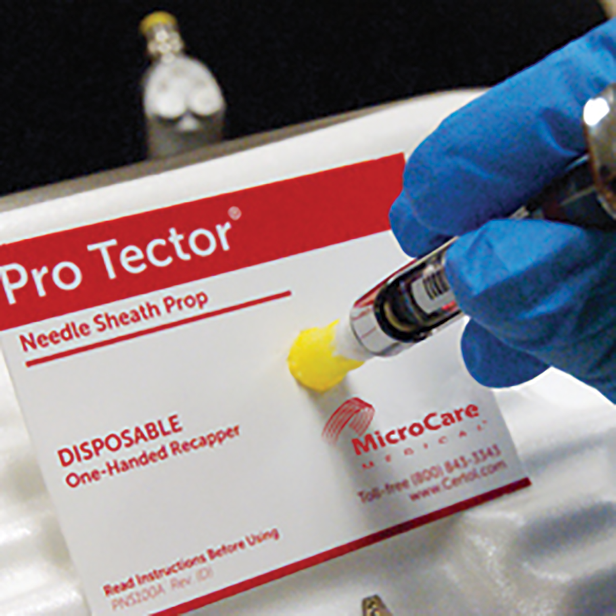 Pro Tector needle sheath prop with a gloved hand holding a syringe.