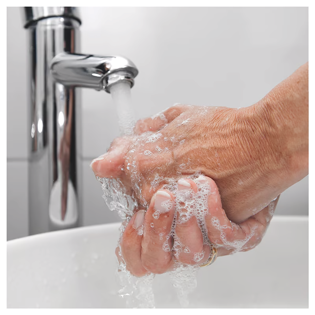 Hands being washed with soap under a running faucet